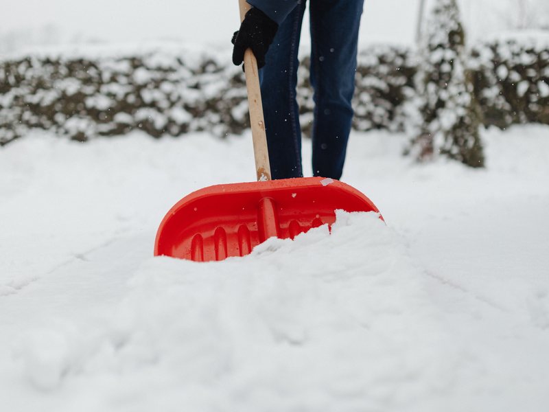 Schneeräumung mit Schneeschieber auf einem Gehweg